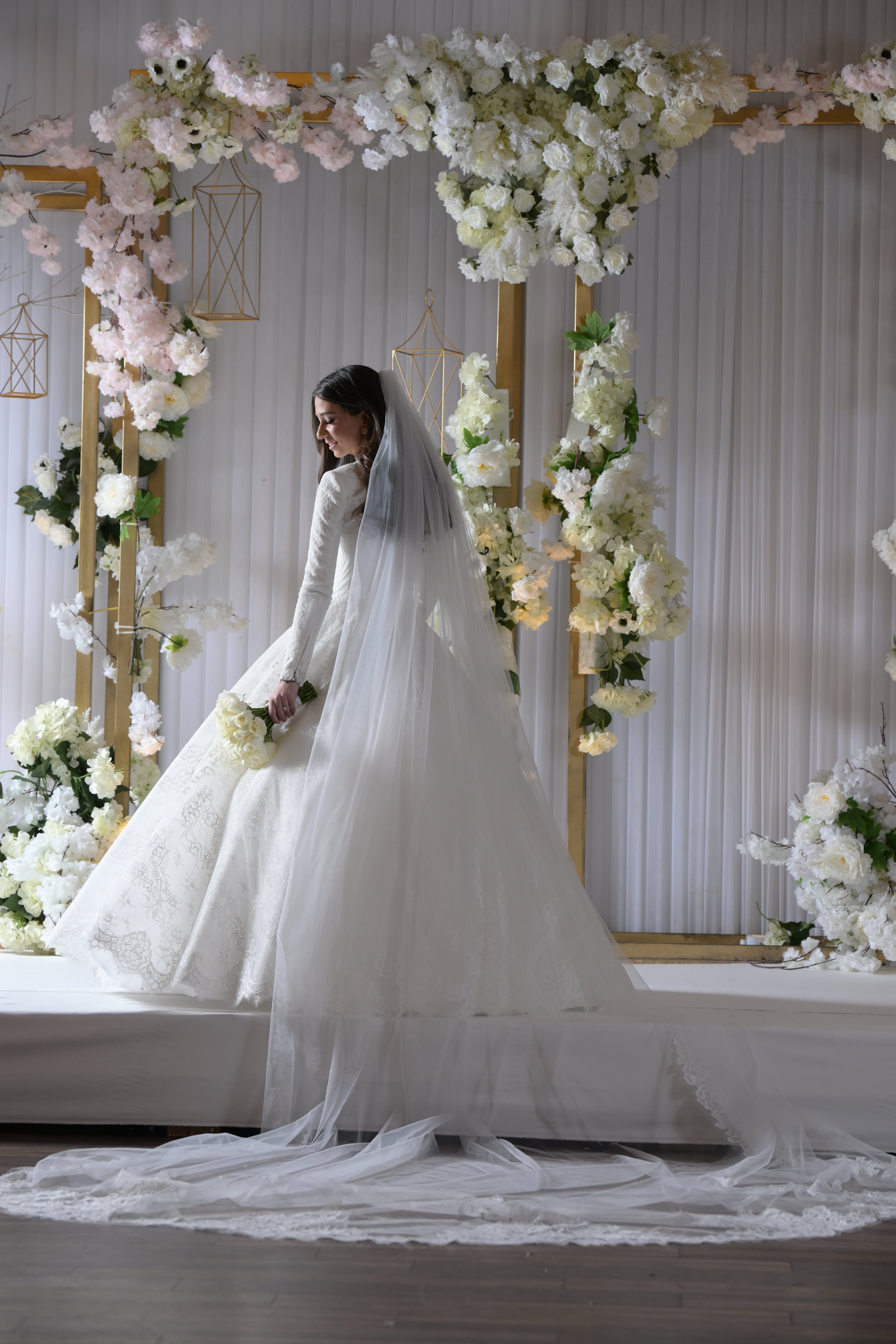 Bride at floral chuppah backdrop with full train