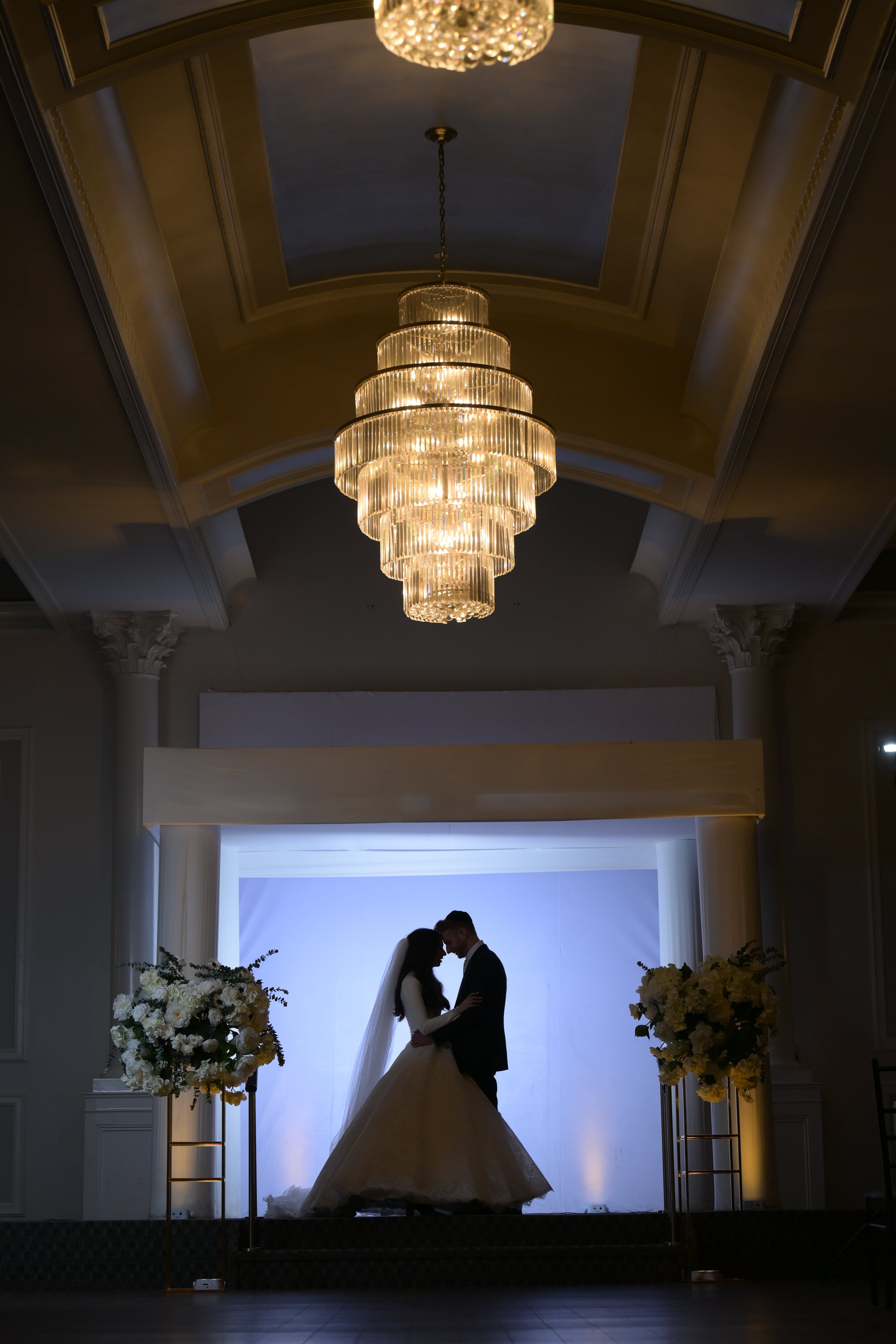 Cinematic ballroom moment under a dramatic chandelier